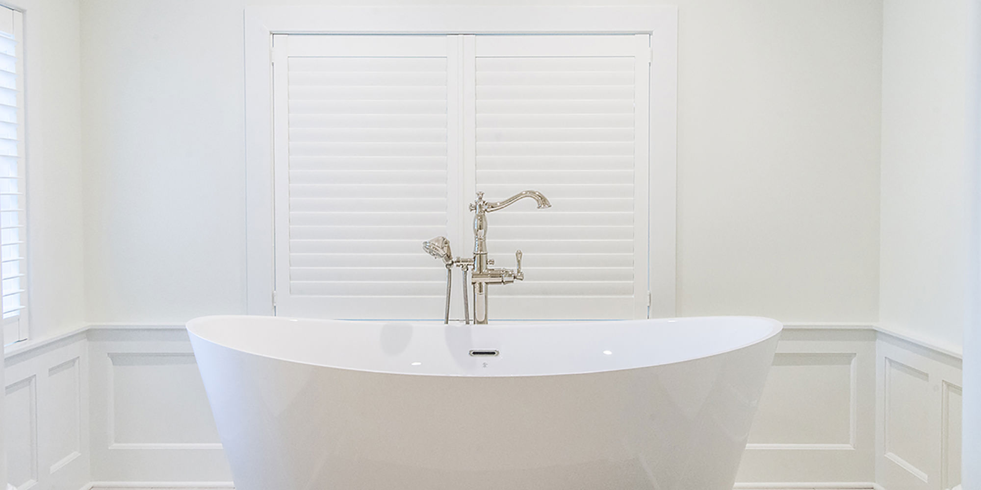 White porcelain free standing soaking tub in white bathroom for custom home client.
